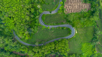 Aerial view of winding road in Malang, East Java, Indonesia surrounded by tropical green hills