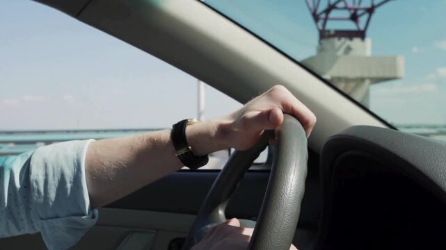 Man driving his car, closeup view of hands on steering wheel. closeup of driver's hands on car steering wheel. Cropped of man driving car. Unrecognizable driver holding hands on steering wheel.