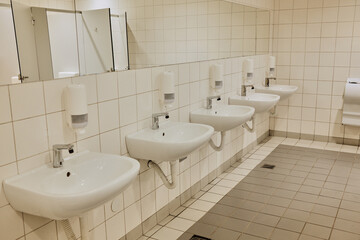 Modern restroom in mall with multiple white sinks, mirrors, and tiled walls. Concept highlights hygiene, cleanliness, and order