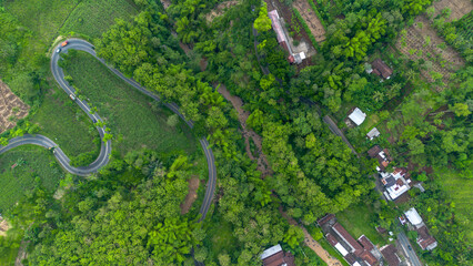 Aerial view of winding road in Malang, East Java, Indonesia surrounded by tropical green hills