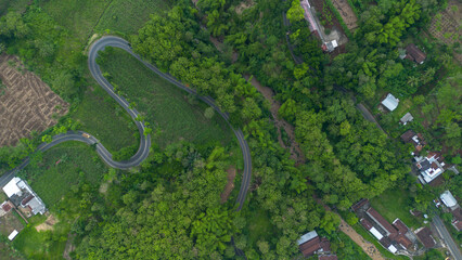 Aerial view of winding road in Malang, East Java, Indonesia surrounded by tropical green hills