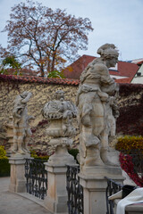 Historic stone statue in autumn garden with ivy-covered wall