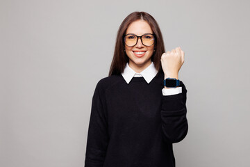 Young fun successful employee business woman corporate lawyer she wear black sweater shirt glasses work in office show blank screen smart watch isolated on plain grey color background studio portrait.