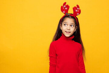 Merry shocked little girl wear red clothes fun decorative deer horns on head posing look aside on area isolated on plain yellow color background. Happy New Year Christmas celebration holiday concept.