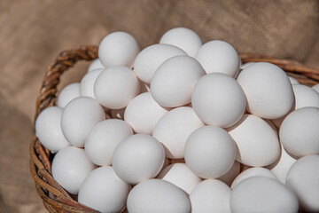 Chicken eggs in a large wicker basket. Countryside outdoor setting