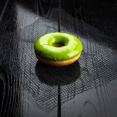 Fototapeta premium Vibrant Green Glazed Donut on Black Textured Wooden Surface