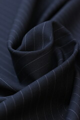 Closeup of luxurious, dark navy cool wool suiting fabric with a subtle, elegant pin stripe pattern,...