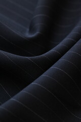 Closeup of luxurious, dark navy cool wool suiting fabric with a subtle, elegant pin stripe pattern,...