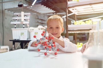 Cute school boy playing with molecular toys in laboratory classroom.	
