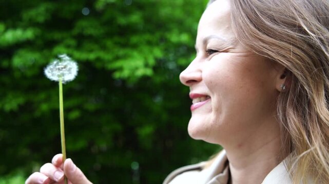 Magical Dandelion Wish, Happy Woman Blowing Seeds Outdoors in Springtime.