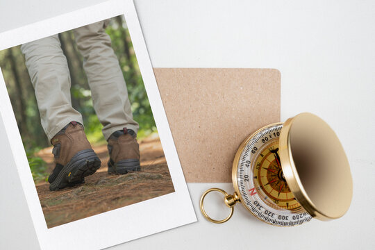 Instant print of a hiker walking in the forest with a card and antique compass on a white background. Mockup or Copy space. Concept of travel - Powered by Adobe