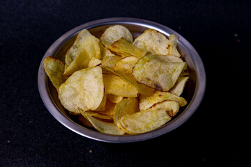 Crispy potato chips served in a silver bowl on a dark background, perfect for snacking during movie nights or gatherings with friends