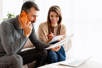 Couple planning home finances with phone call and paperwork
