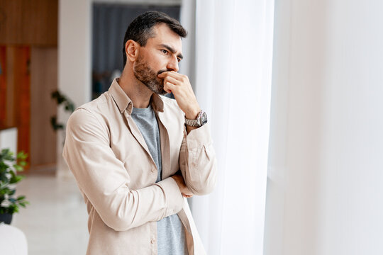 Thoughtful man looking out window contemplating future