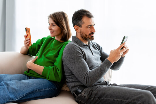 Pregnant couple distracted by smartphones ignoring each other