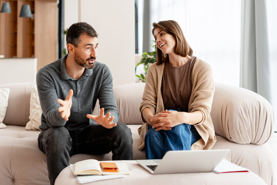 Couple discussing financial planning at home on sofa