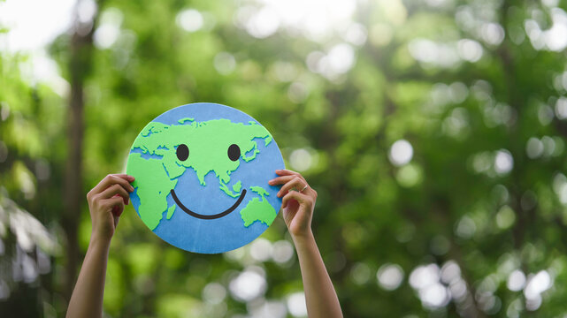 Hands holding a smiling world paper cutout to eco-friendly and saving the planet for responsibility to sustainable environment, environmental awareness. climate change, Earth Day and ESG concept
