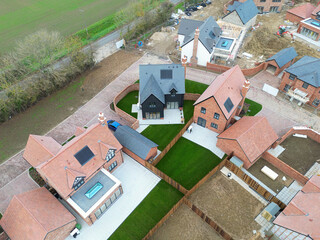 Drone top down view of recently built expensive detached family homes. A large conservatory and glass lantern is seen on the left.