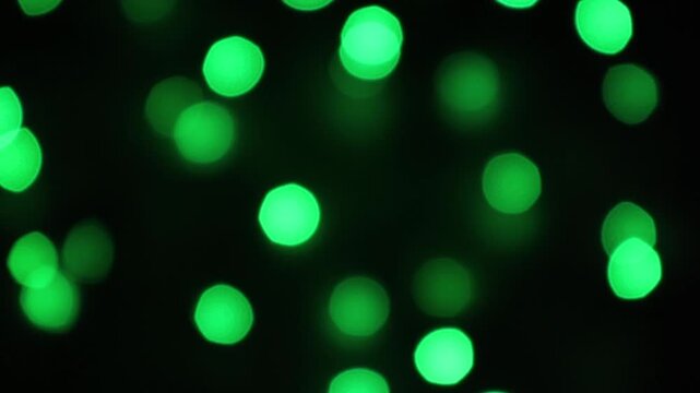 Abstract green bokeh lights gently shimmering on a dark background. Technology, festive, or nature concept. Green Christmas Bokeh. Festive holiday or St. Patrick's Day abstract lights background.