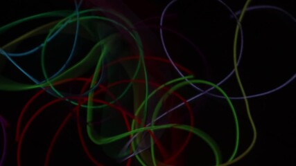 Close-up of tangled, colorful neon EL wire (electroluminescent wire) flickering and glowing on a black background. Abstract Neon Christmas Lights. Colorful glowing EL wire creates a festive background - Powered by Adobe