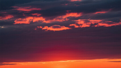 Fototapeta premium Vibrant sunset with dark clouds illuminated by the intense orange and red light below them