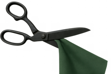 Black tailor shears in action, cutting a piece of folded green fabric. Isolated image with a transparent background