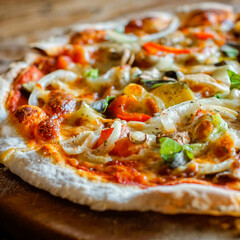 Close-up of homemade pizza with melted cheese, tomato sauce, and vegetables on rustic wooden table, showing authentic Italian cuisine and delicious texture.