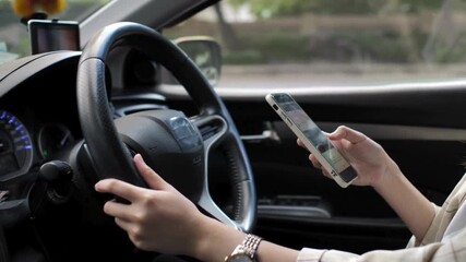 hand holding smart phone, steering wheel and car interior background. Person holding cell phone in one hand and the other hand on steering wheel. man using phone while driving behind the wheel. - Powered by Adobe