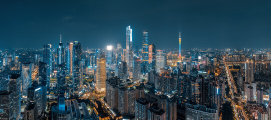 Naklejka premium Aerial panorama of the illuminated modern city skyline and financial district with glowing skyscrapers at night in Guangzhou.