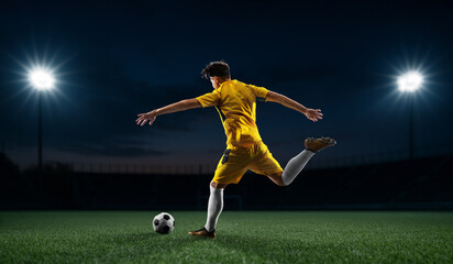 Composite image of soccer player in yellow gear striking the ball with precision under lights. Concept of sports branding visuals, football energy, digital promotion, and performance storytelling.