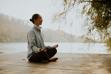 Calm reflection of a woman meditating by the serene lakeside at sunset
