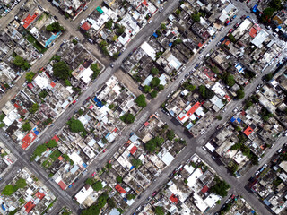Aerial top-down view high altitude of slum a heavily populated urban informal settlement characterized by substandard housing and squalor poor living conditions streets and rusty metal home roof tops