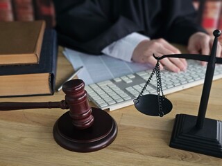 A judge prepares for a court hearing, using a gavel and scales on a table covered with law books concept