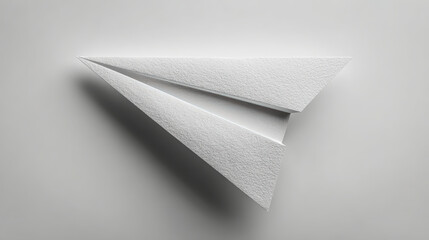 A simple paper airplane crafted from textured paper, depicted against a soft grey background, symbolizing minimalism and creativity.