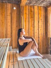 Woman relaxing in wooden sauna. Calm and warmth.
