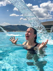 Woman under water stream in pool. Joy and energy.