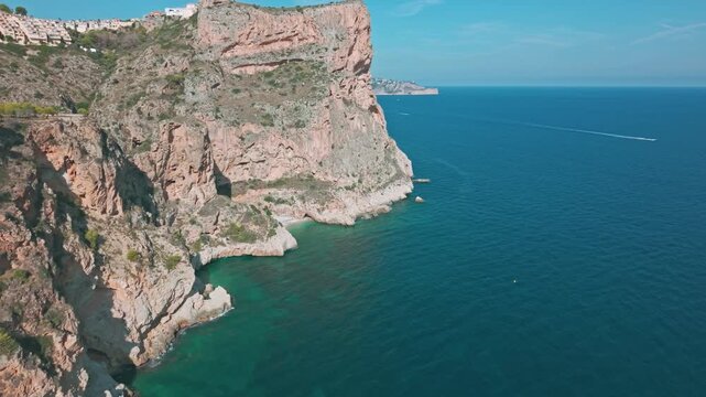 Aerial drone footage of Cala del Moraig cliffs and turquoise Mediterranean sea in Benitatxell, Spain. Stunning coastal landscape with dramatic rock formations.