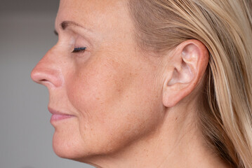 Profile close up of mature woman face with visible skin texture and natural aging signs. Concept of skincare, beauty, health, dermatology, and realistic aging process.