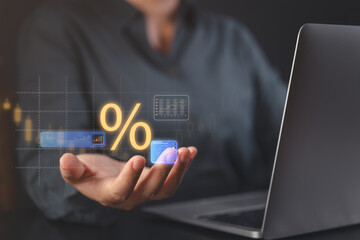 Hand holding holographic percentage with market analytics near laptop for interest rate finance and investment data visualization