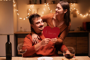 young smiling man and woman hugging has romantic dinner at home. Happy couple in love. Valentines day concept.