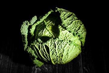 savoy cabbage on black wood background top view