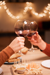couple in love clinking glasses of wine together during their date or Valentine's Day at home. close-up