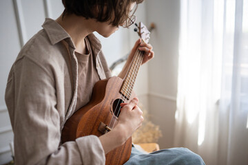Focused woman learner practice chord transitions on small string guitar, muscle memory and timing....