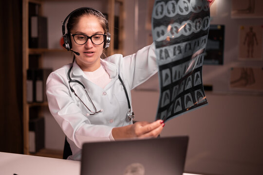 Telemedicine concept. female doctor talking with patient on laptop and shows x-ray to screen. Medical worker working during night shift in hospital