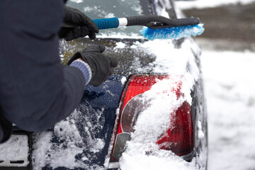 Cleaning snow from a car in winter at a residential area