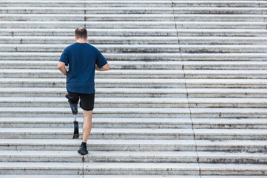 Man with a prosthetic leg going up the street stairs, walking exercise with an artificial limb. Mobility and disability concept. - Powered by Adobe