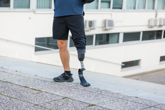 A man exercises outdoors on a sunny day, showing strength and determination with his prosthetic leg.