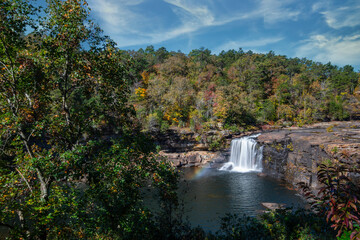 Majestic waterfalls cascading into a serene pool at Little River Canyon during a vibrant autumn day