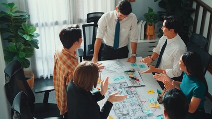 Group of diverse team planning strategy while sitting at table with project plan. Top aerial view of smart business people working together to brainstorm and design house construction. Alimentation.