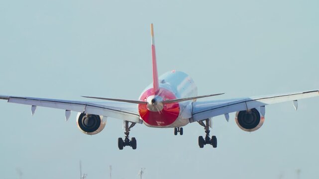 Passenger aircraft descending for landing in slow motion during daytime with visible landing gear
